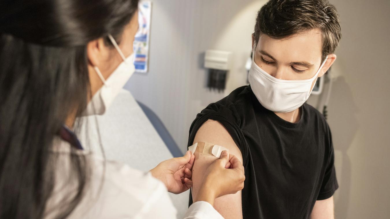 nurse applies bandage to vaccination spot on man's arm