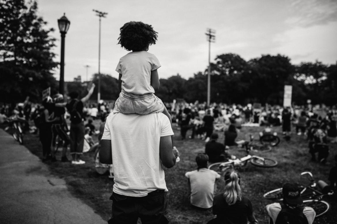 Child sits on parent's shoulders at a rally