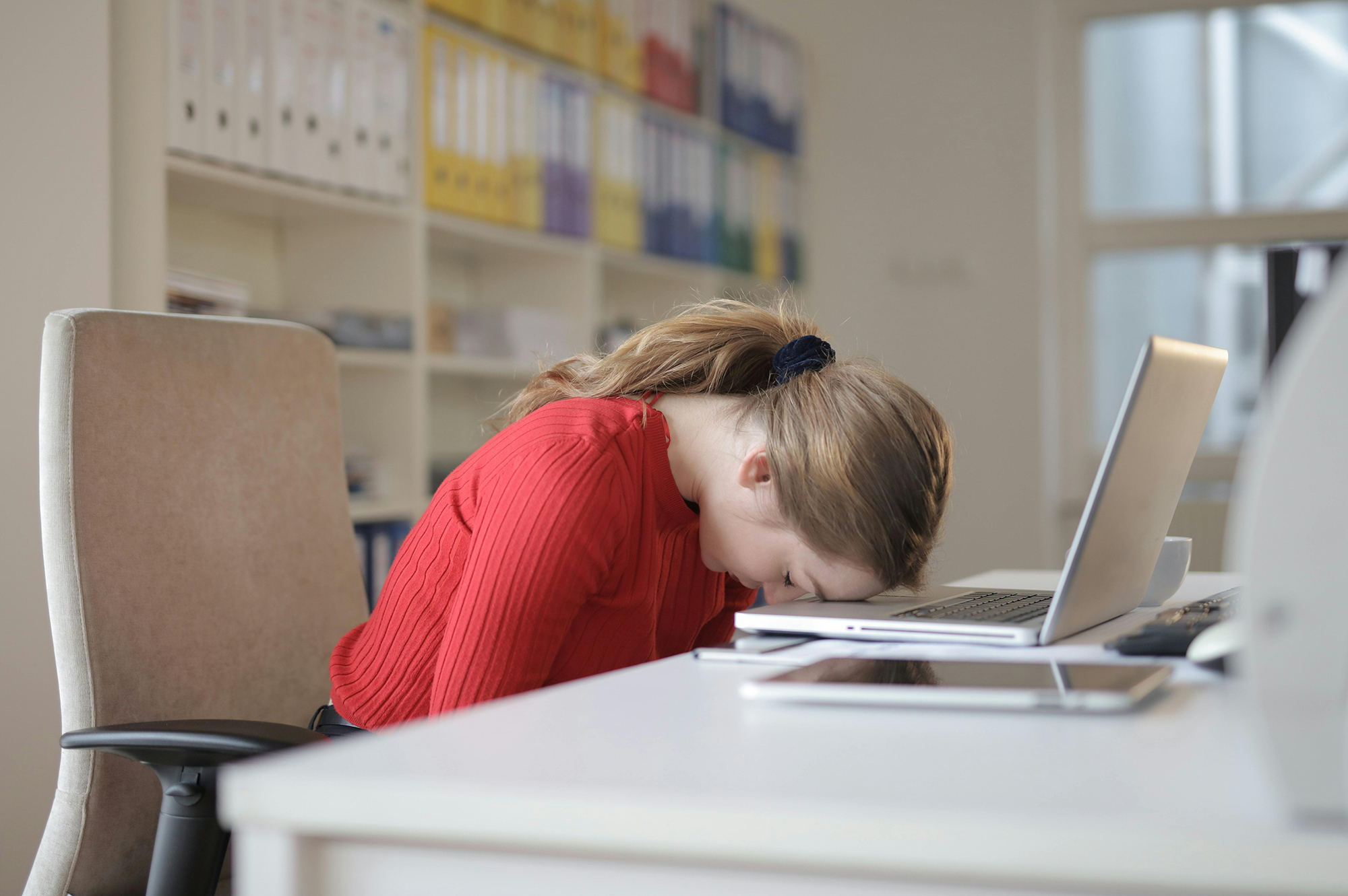 person sitting at desk with head down on laptop keyboard