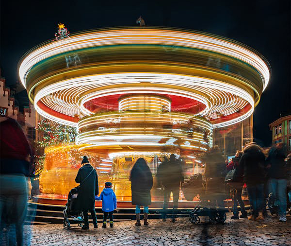 Carousel spins at night with people milling about around it