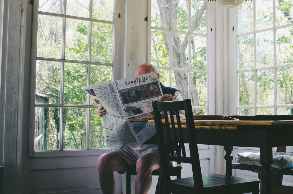 Man sits at kitchen table reading newspaper