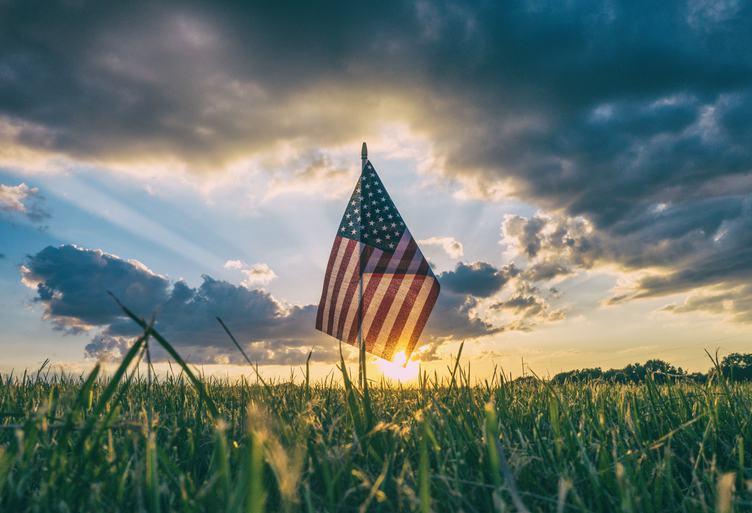 American flag in a field at sunset