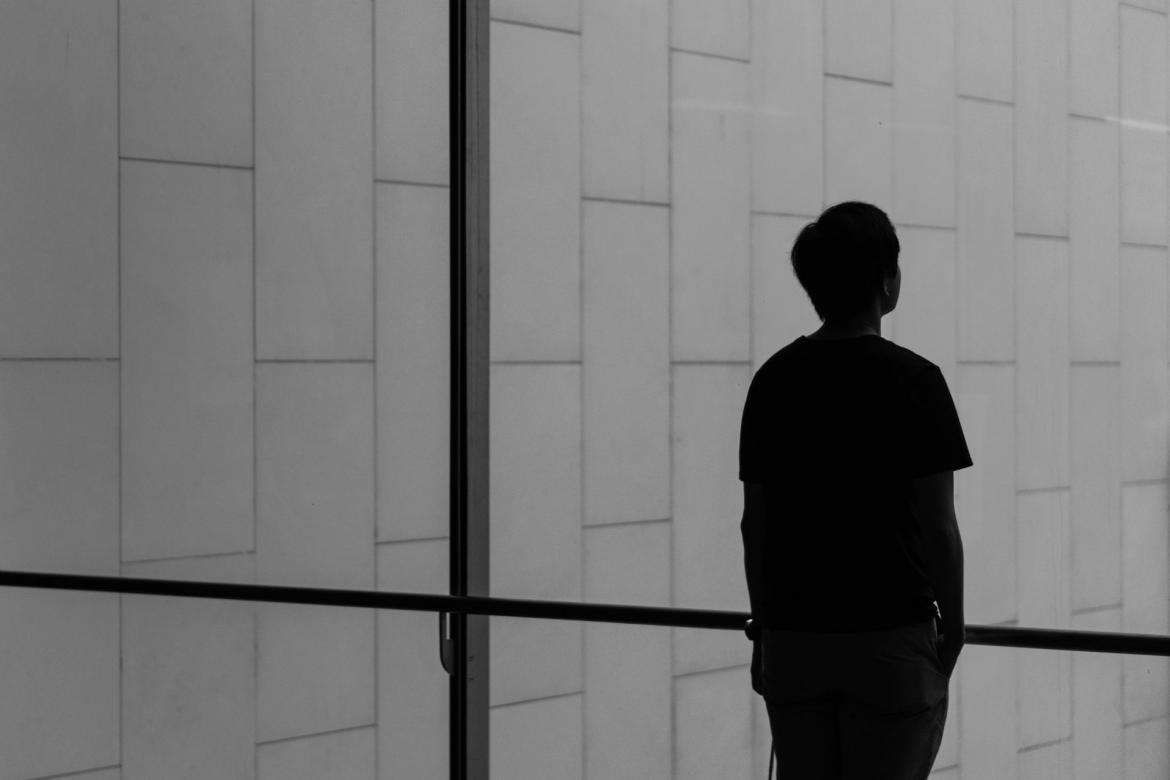 Black and white image of person looking sadly out a window