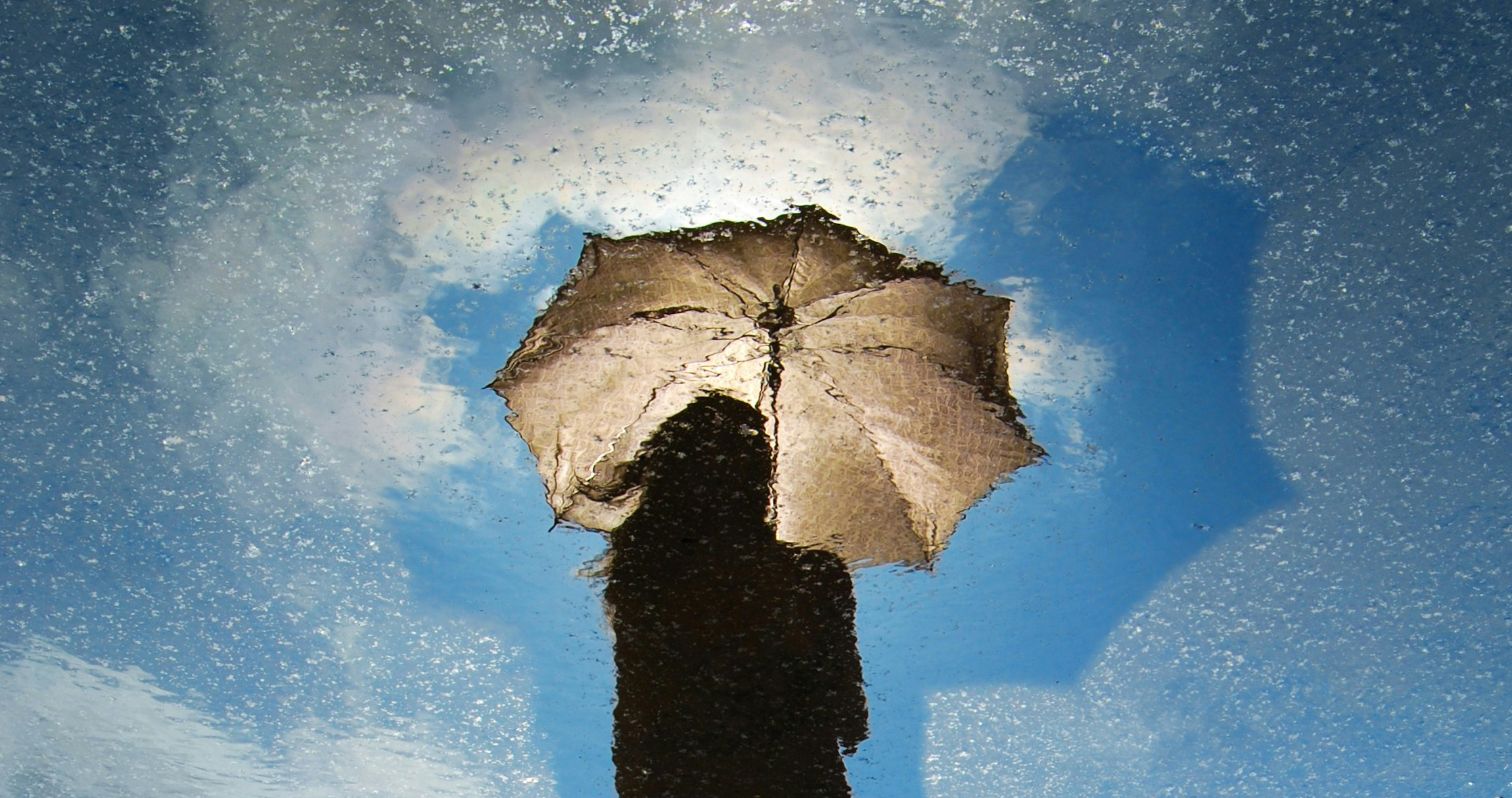 Water reflection of person holding umbrella