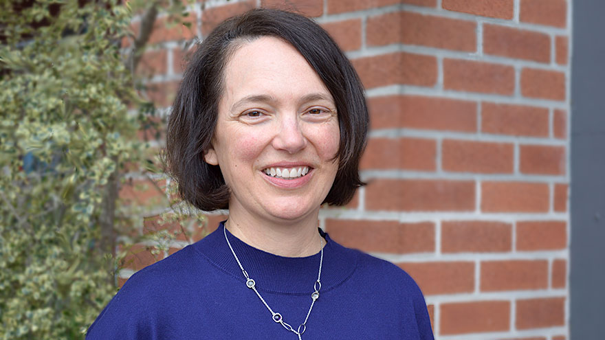 Amy Jessen — white woman with dark hair in a bob cut wearing an indigo top and silver necklace