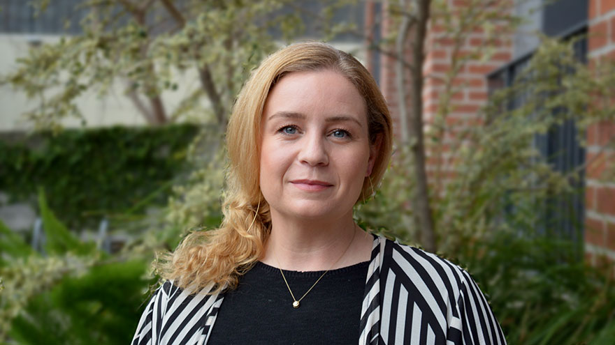 Jessica Allanson — woman with blonde hair, black top and black and white striped jacket