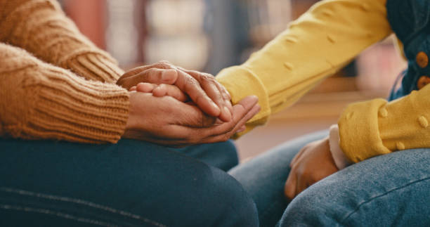 A person shows compassion by holding another person's hands in their own