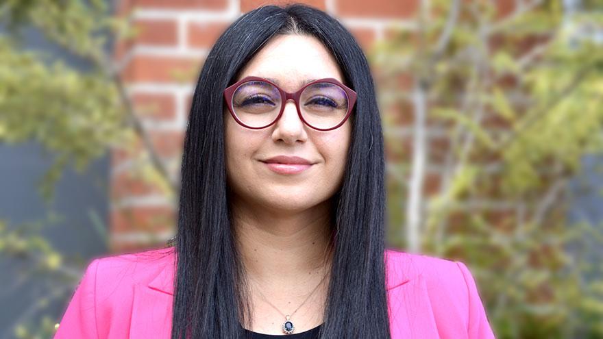 Ana Dolatabadi: woman with black hair, magenta jacket and maroon-framed glasses