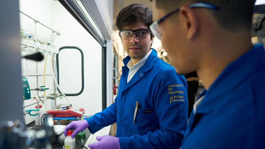 Two people in blue uniforms working in a lab