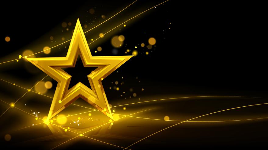 Yellow star with black background. Glittery light is coming off the star. 