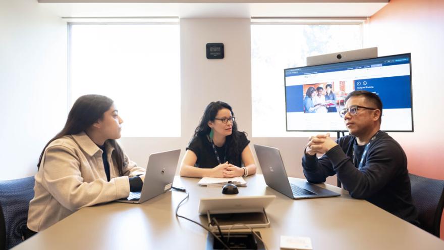 two women and one man sit at a conference table