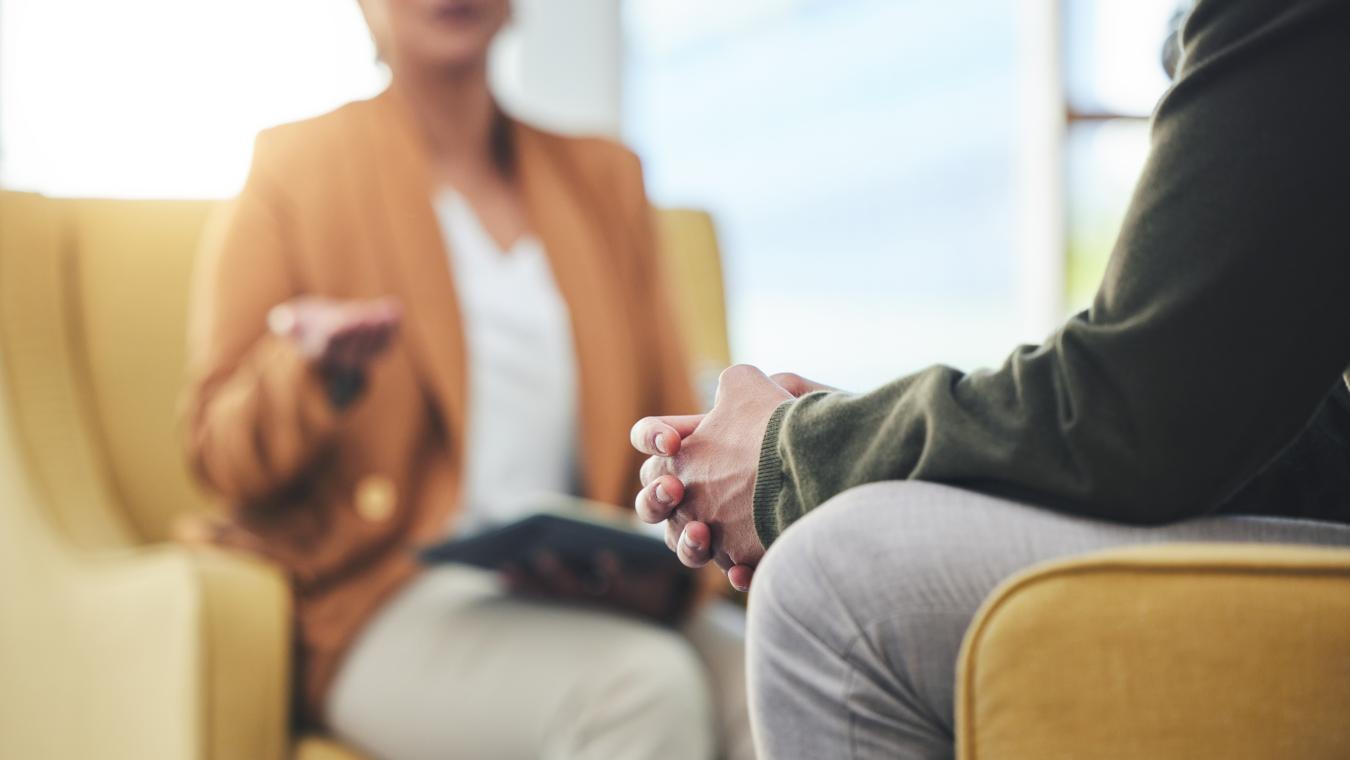 Therapist listening to another person. Both people are shown from the neck down.