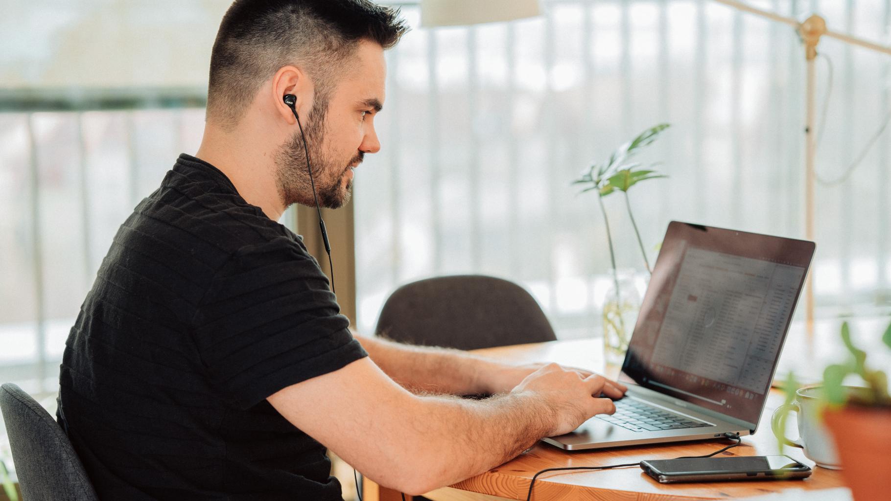 seated man works on laptop computer