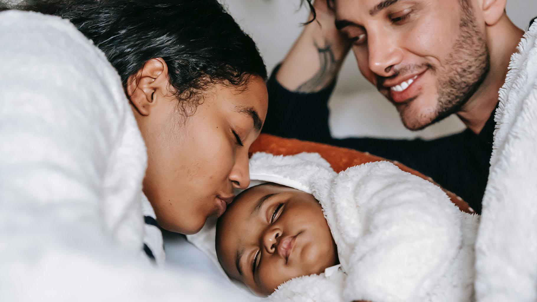 Parents cuddle with newborn baby