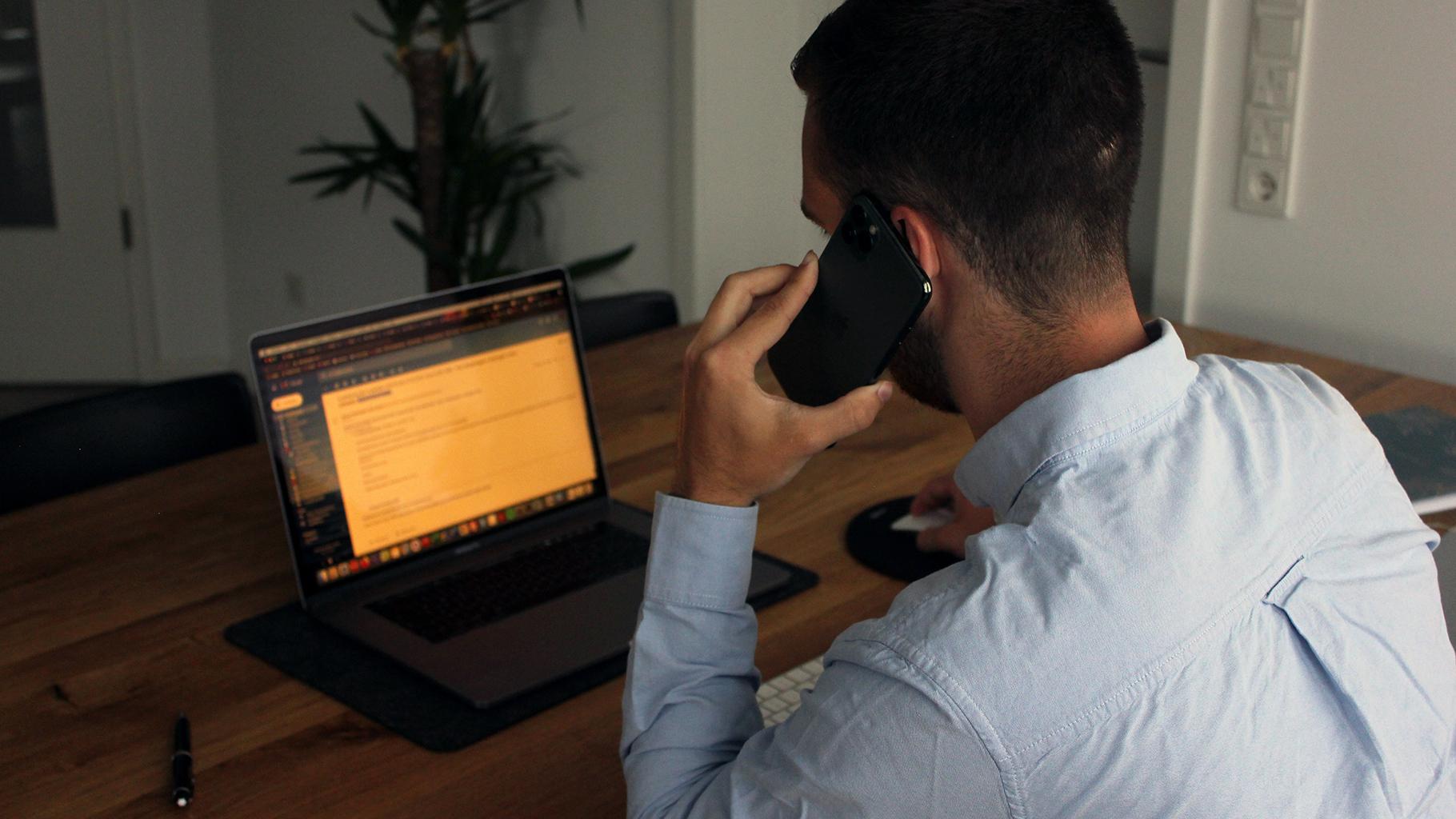 Man on his phone looks at laptop