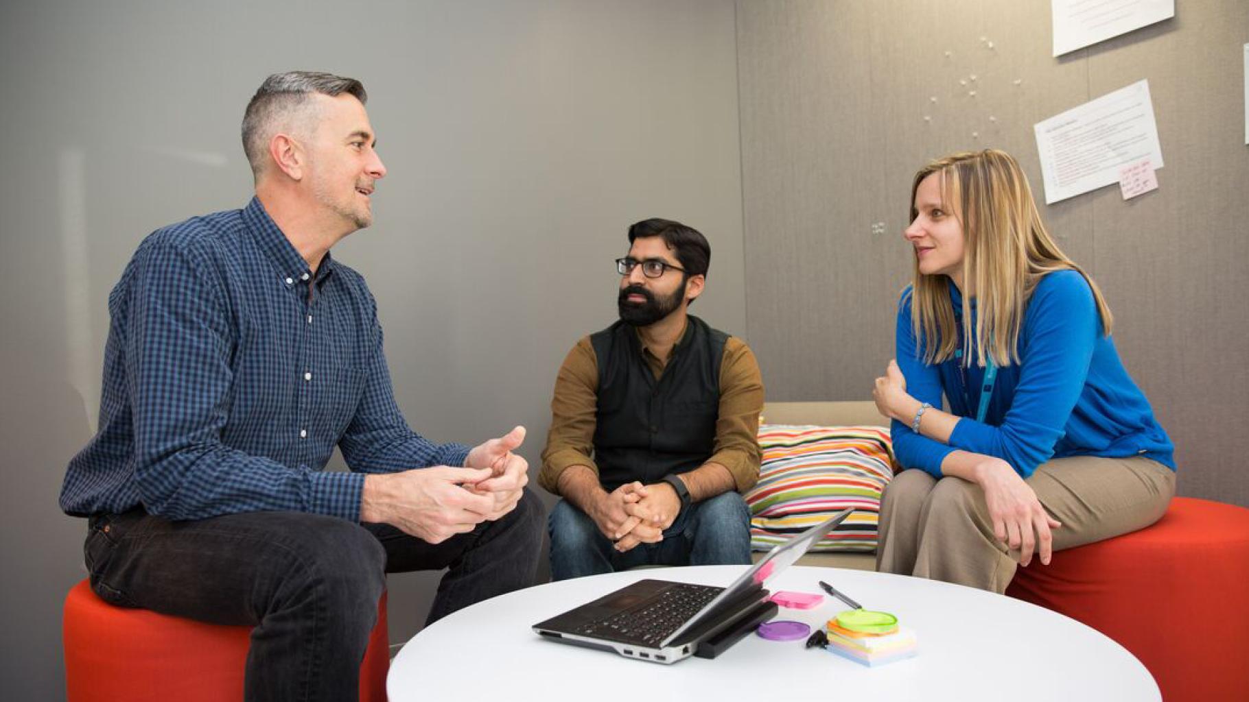 Employees sitting on orange couches talk