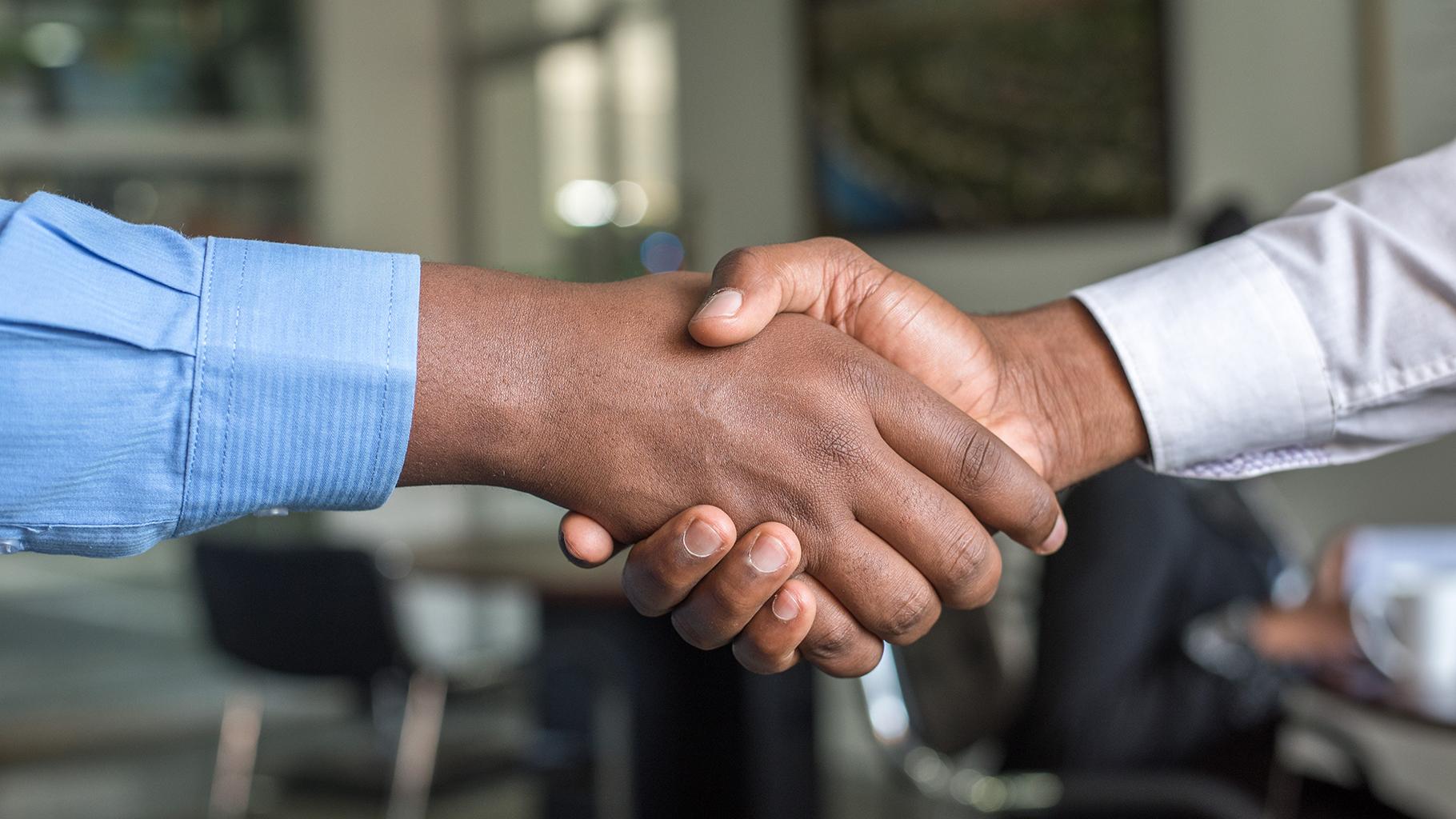 Two people shaking hands, only wrist and hands are shown.