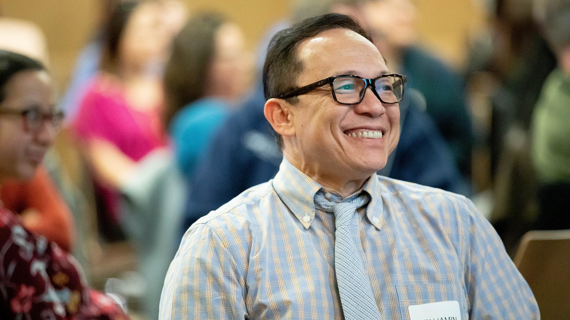 Staff member in audience smiles during presentation