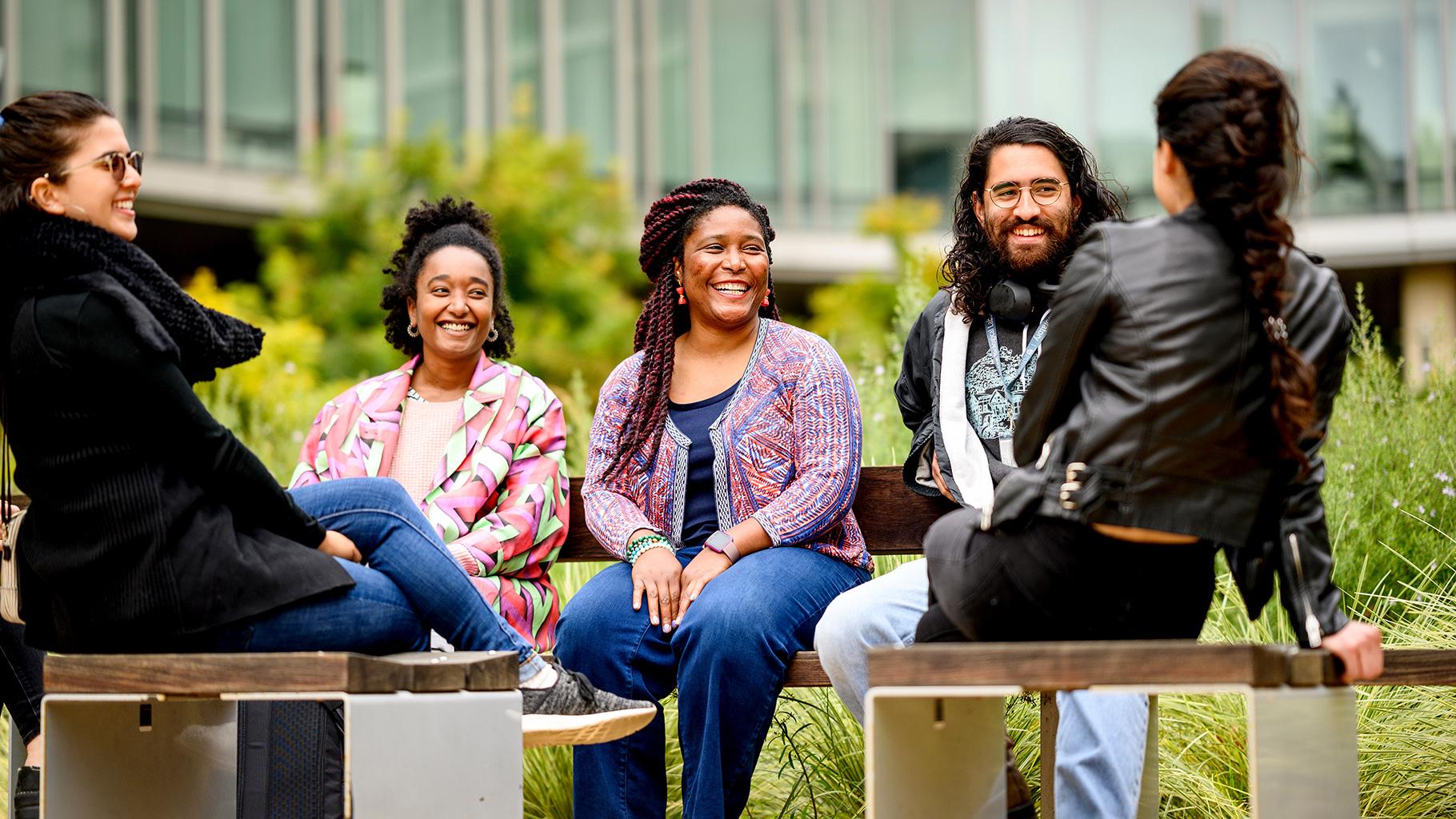 Five people sitting outside talking