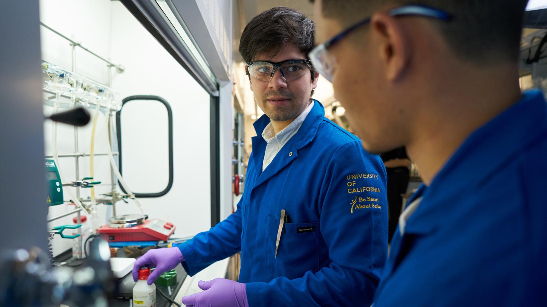 Two people in blue uniforms working in a lab