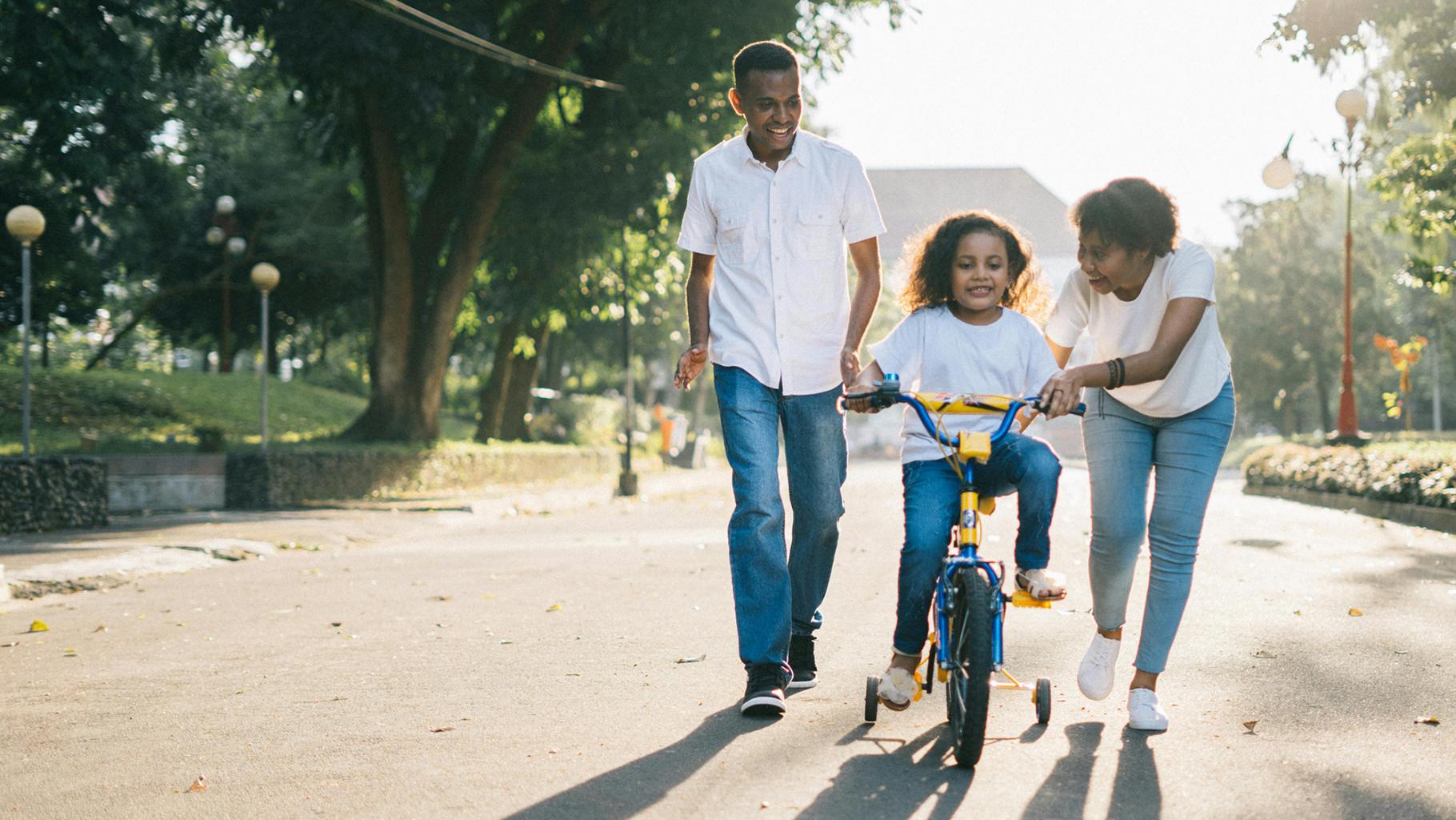 Parents help child ride bike