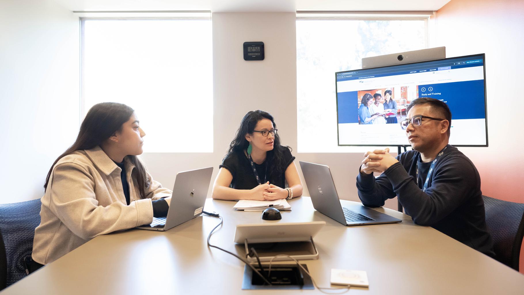 Three UCSF teammates work in a huddle room